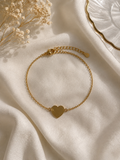 Gold-toned fine-chain bracelet with a polished heart charm and adjustable extender, laid on cream fabric