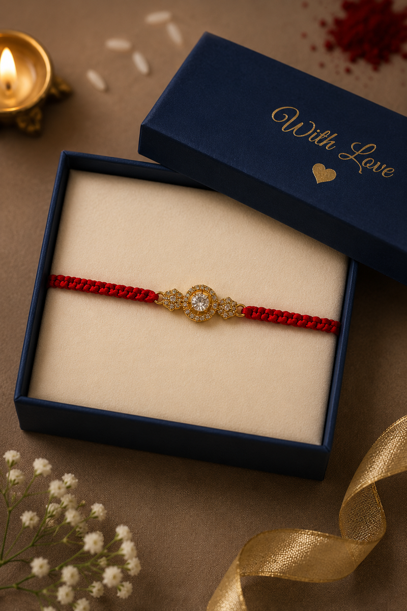 Gold oval solitaire rakhi on a red thread in a navy With Love gift box