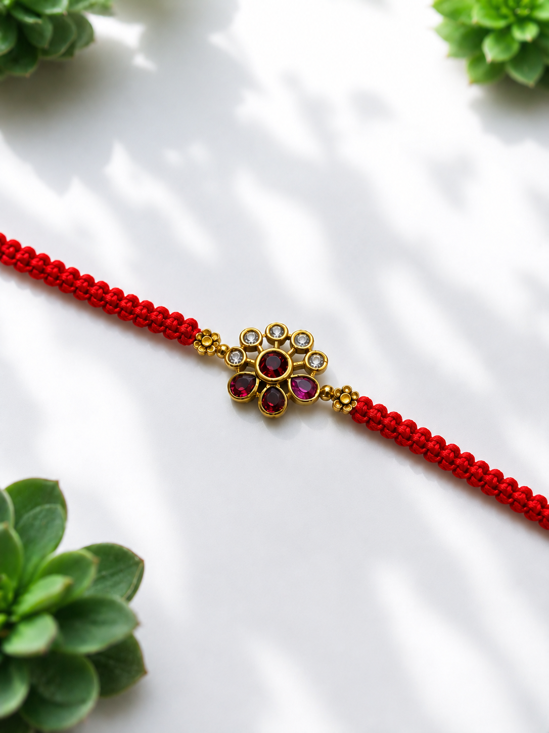 Gold petite floral rakhi on red thread