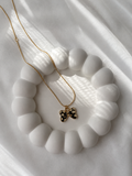 Gold-toned butterfly pendant necklace with black spotted enamel laid flat on a white surface