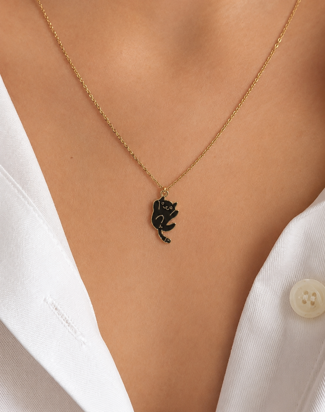 Close-up of the black cat pendant necklace worn over a white shirt