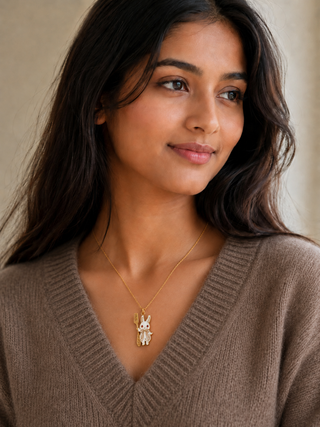 Model wearing the gold-toned bunny charm pendant necklace with a brown V-neck sweater
