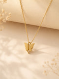 Gold-toned butterfly pendant on a fine chain resting on a cream surface with dried flowers