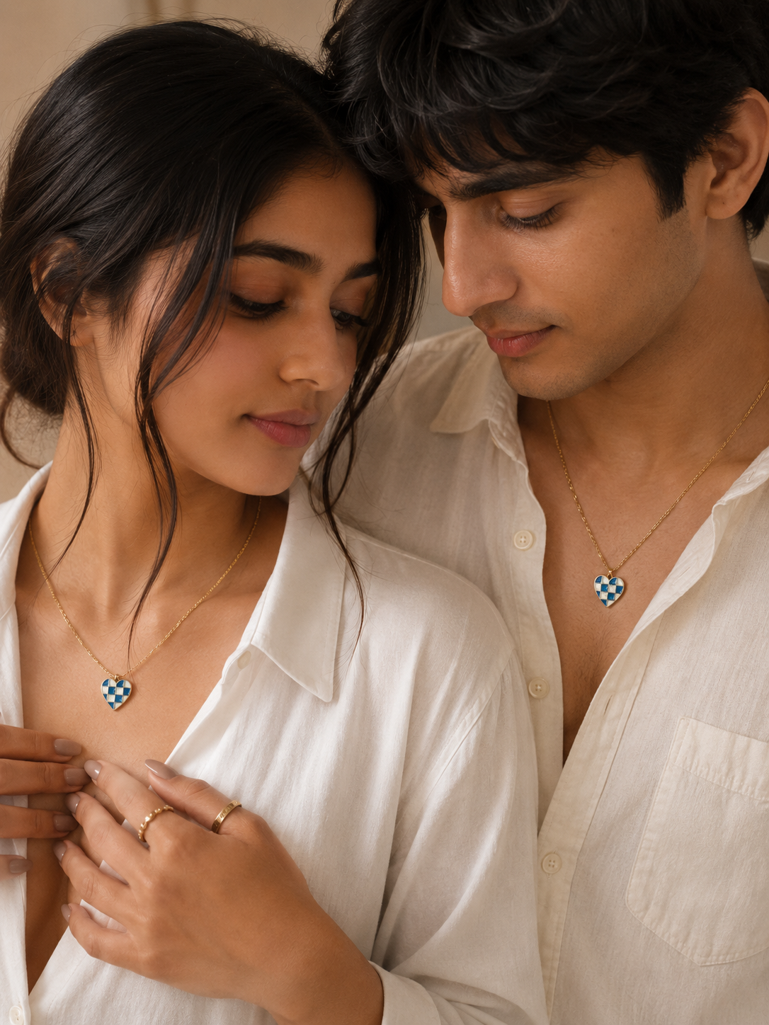 Two models wearing the checkerboard heart pendant on gold-toned chains in white shirts