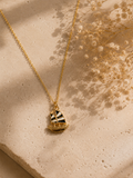 Gold-toned sailboat pendant with black and white enamel sails on a fine chain on stone