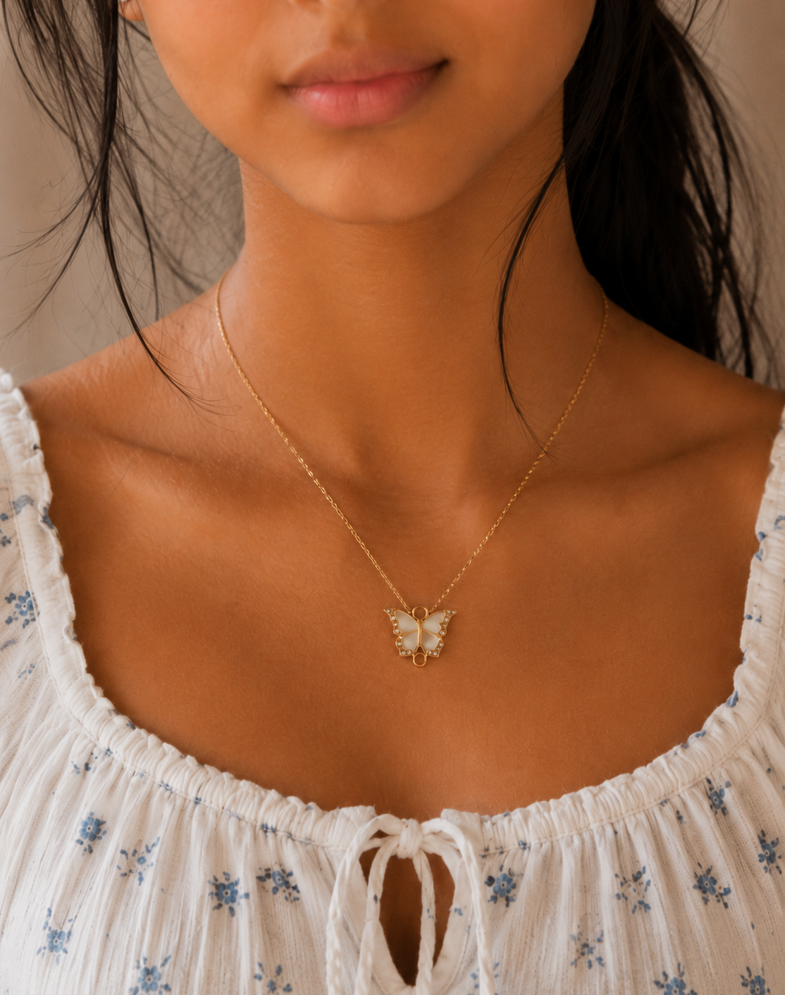 Woman wearing the crystal butterfly pendant necklace with a floral white top
