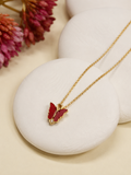 Gold-toned butterfly pendant necklace in red enamel resting on white stones