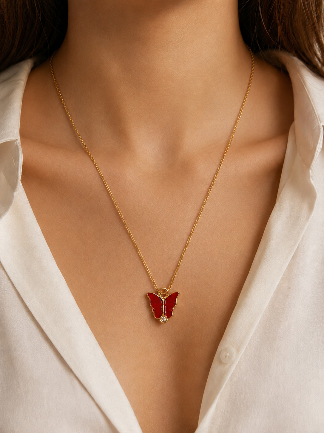 Woman wearing the red enamel butterfly pendant necklace with an open white shirt