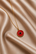 Gold-toned red enamel daisy flower pendant necklace on champagne satin