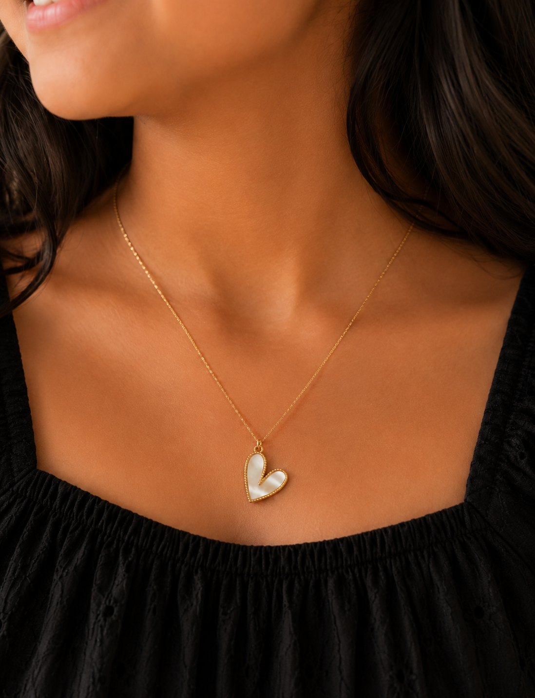 Woman wearing the mother-of-pearl heart pendant necklace with a black top