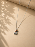 Silver-toned necklace with a rainbow and cloud enamel charm reading BEST on tan fabric