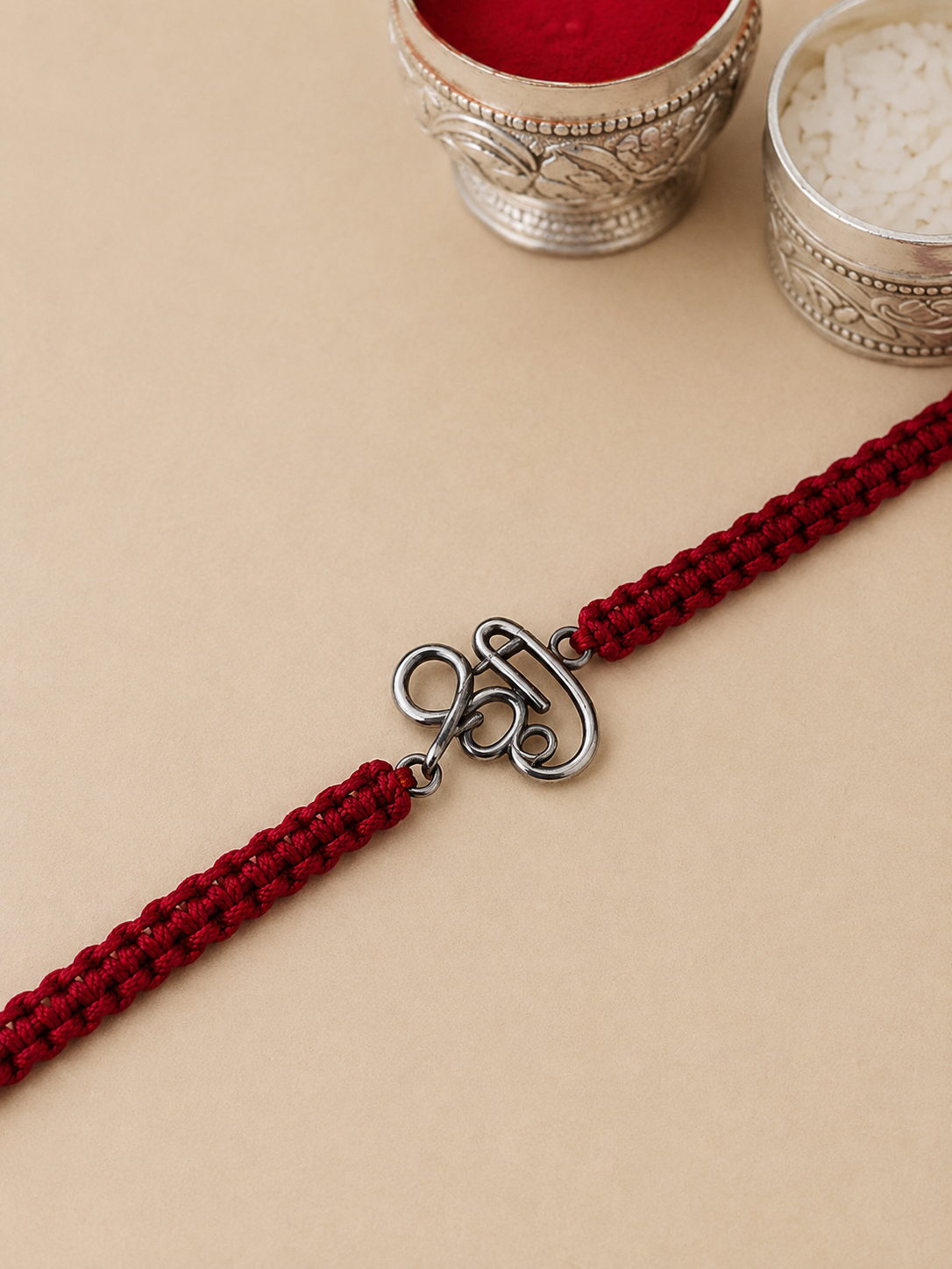 Silver Om red thread rakhi detail
