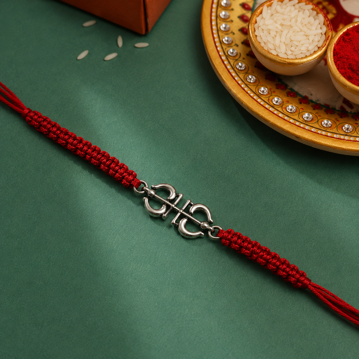 Ornate silver Om red thread rakhi