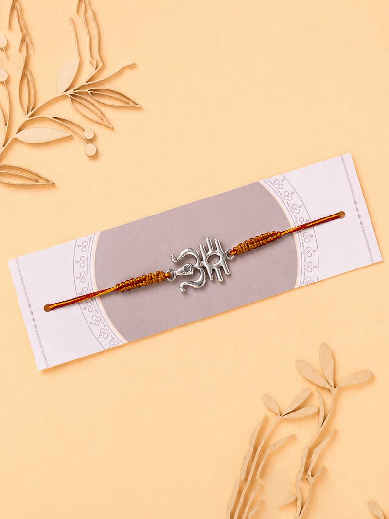 Silver calligraphic Om rakhi on a saffron beaded thread on a card