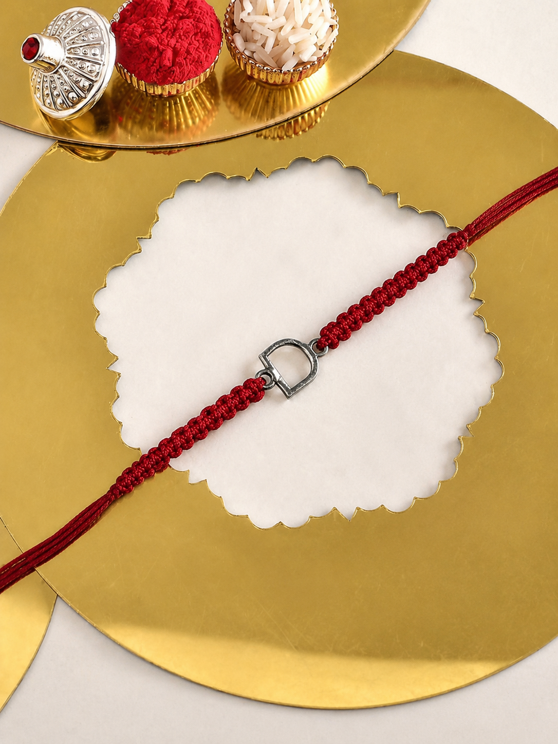 Silver initial D rakhi on a red thread on a Happy Raksha Bandhan card